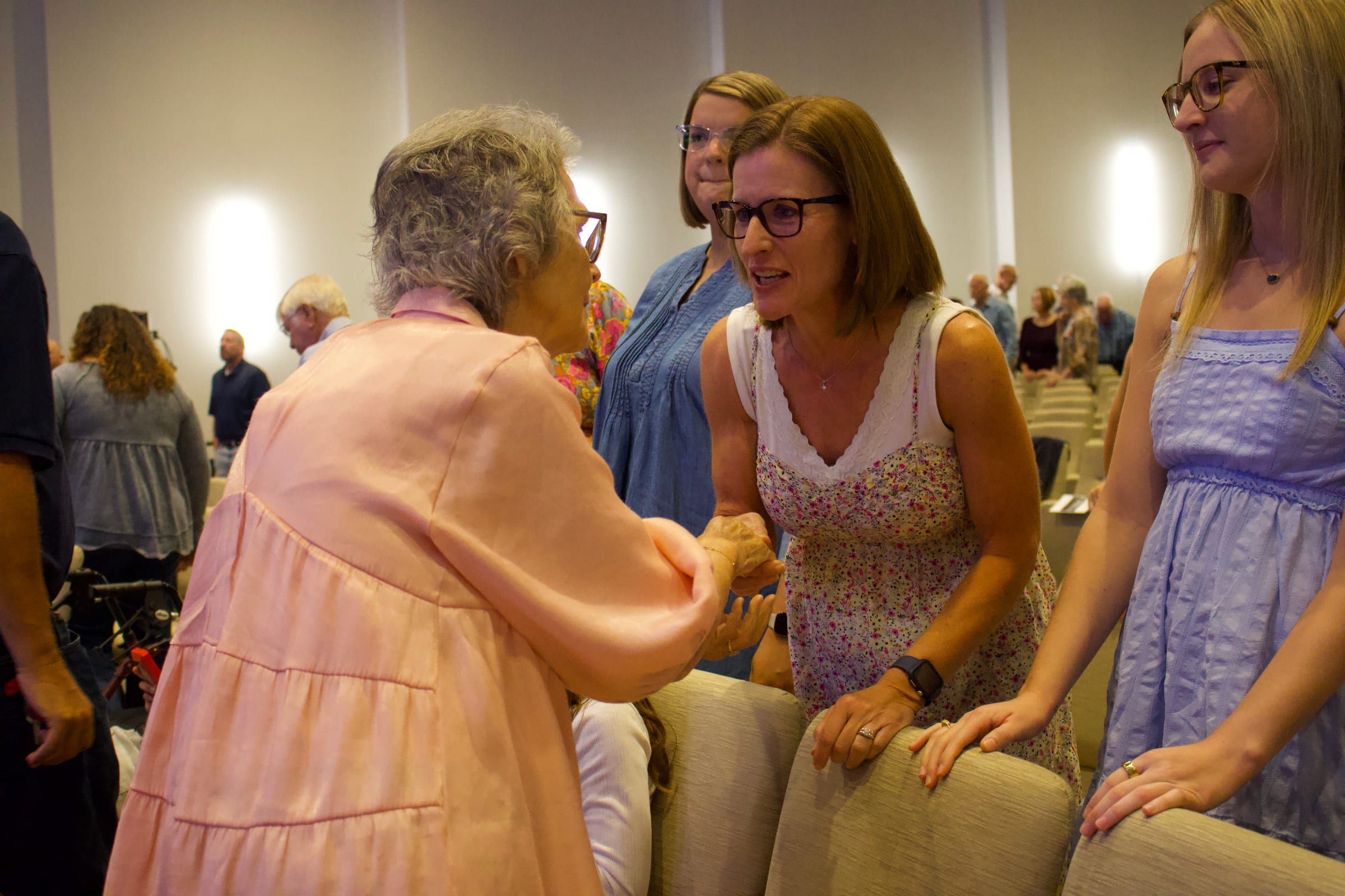 Church members greeting one another warmly in the worship center.