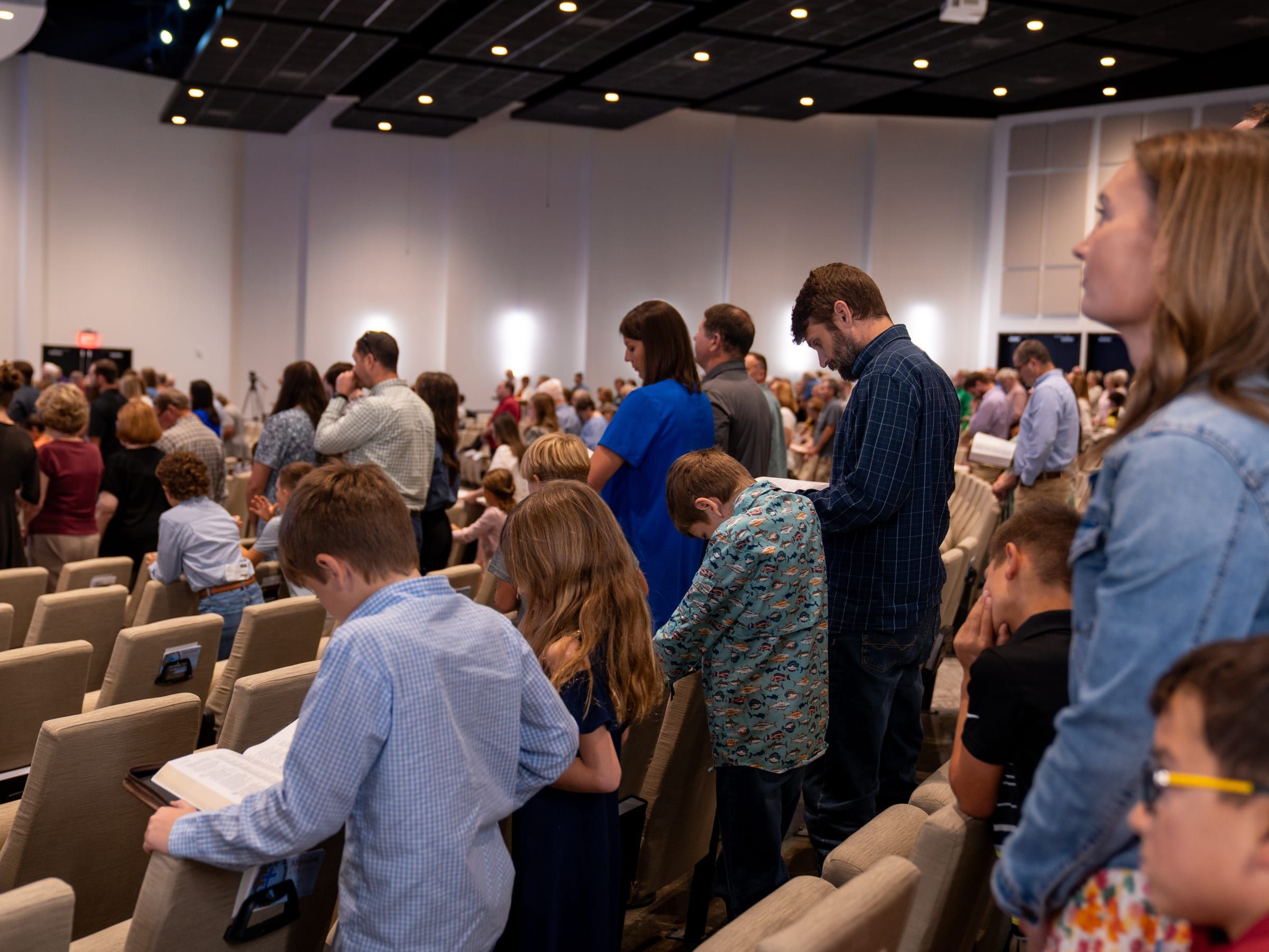 Church members of all ages following along in their Bibles during a Sunday service.