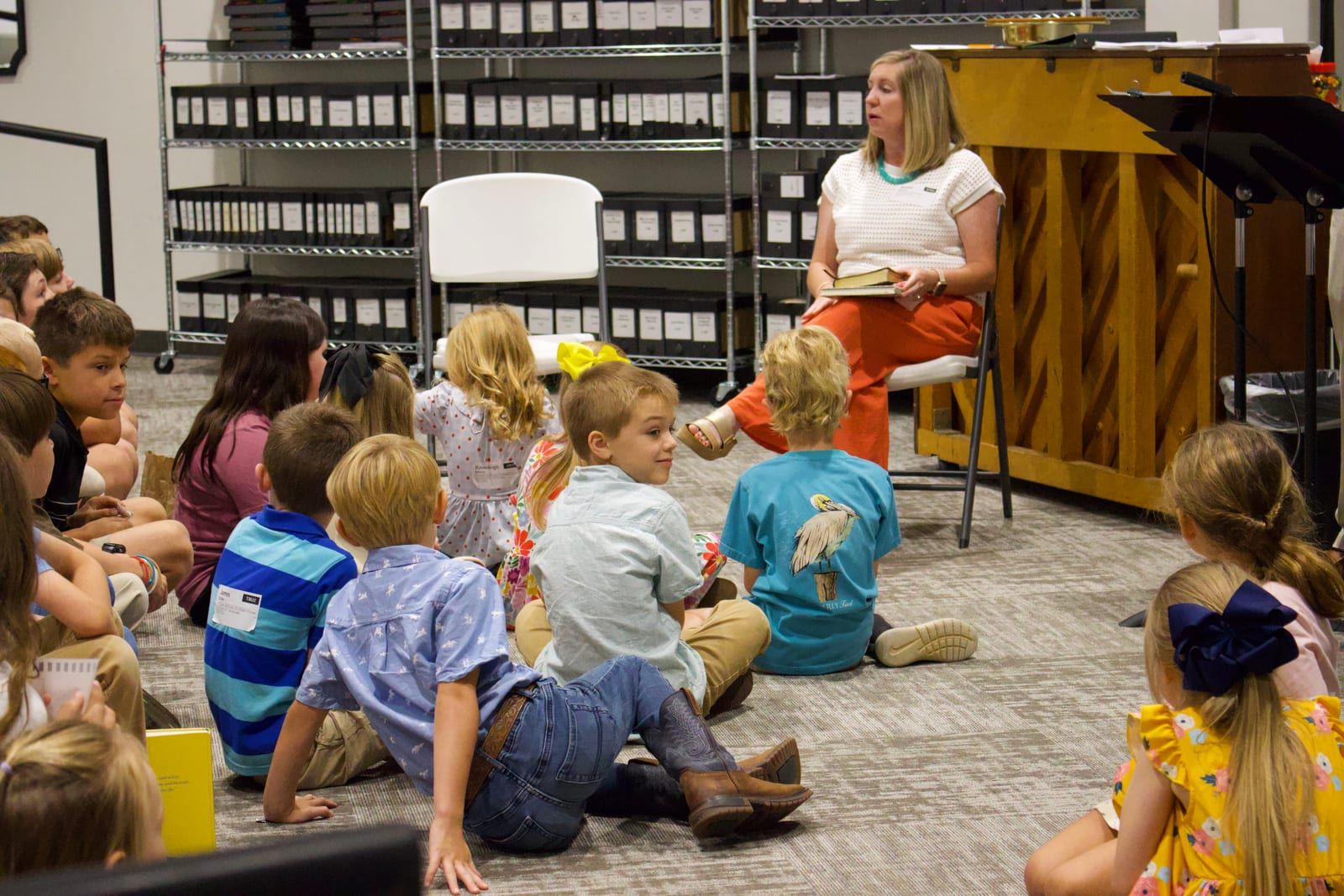 A teacher leading a Bible lesson as children sit on the floor and listen.