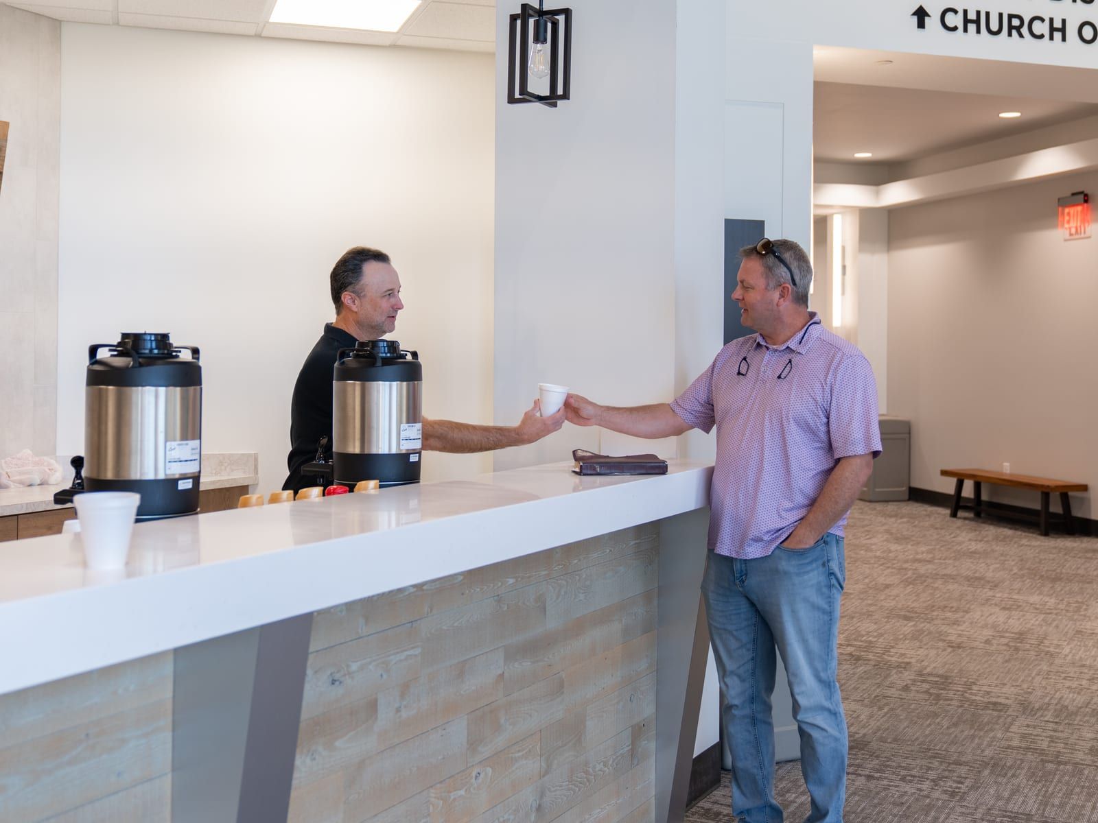 A volunteer serving coffee to a member at the lobby coffee bar.