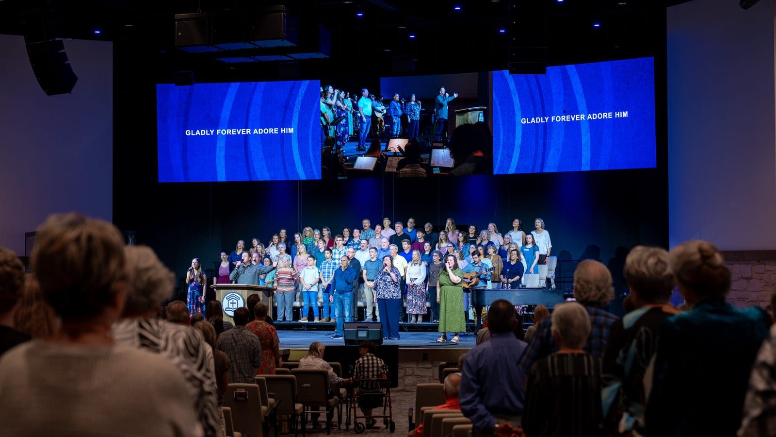 The congregation worshipping with the choir on stage during a Sunday service.