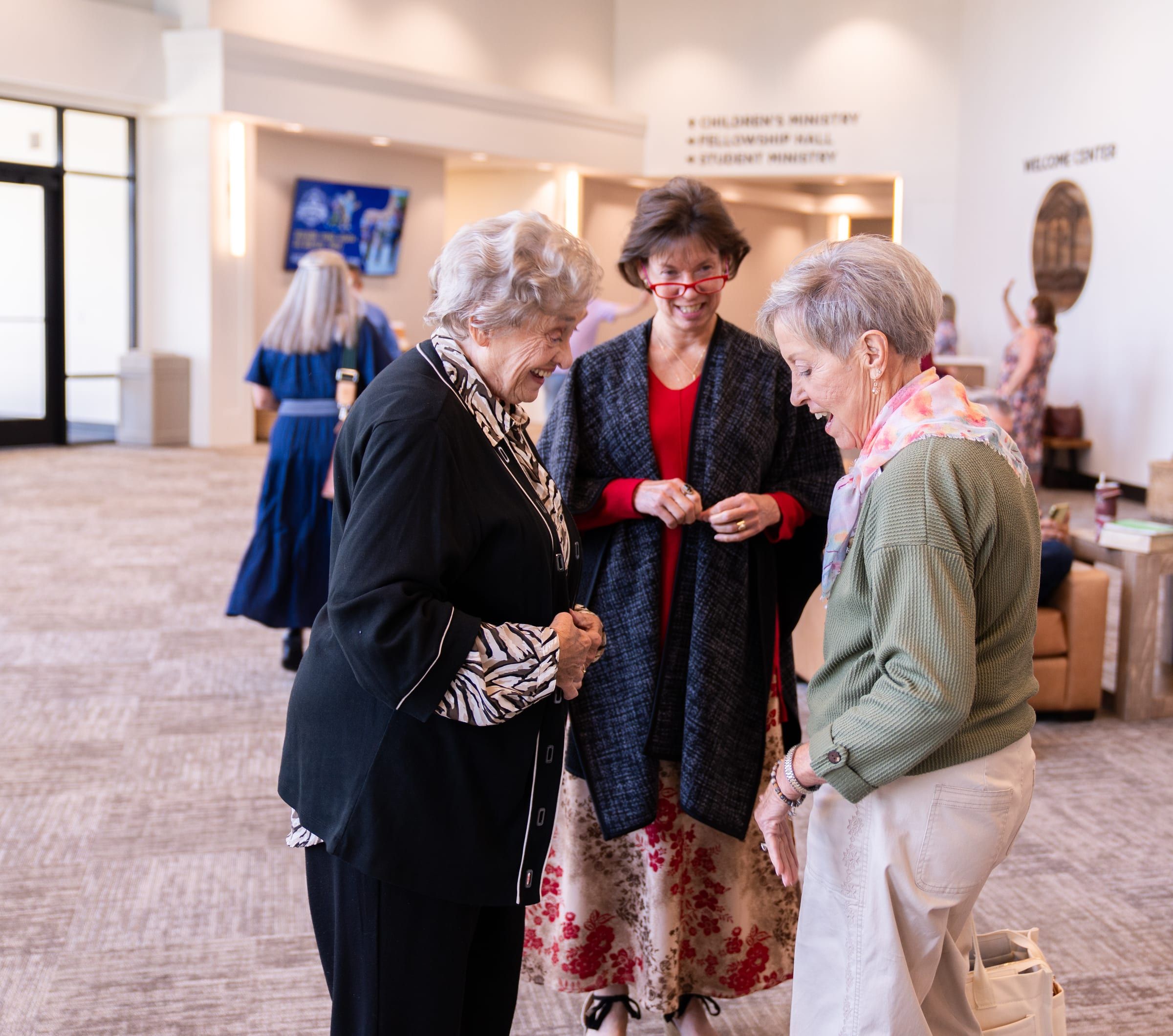 Three women talking together in the church lobby.