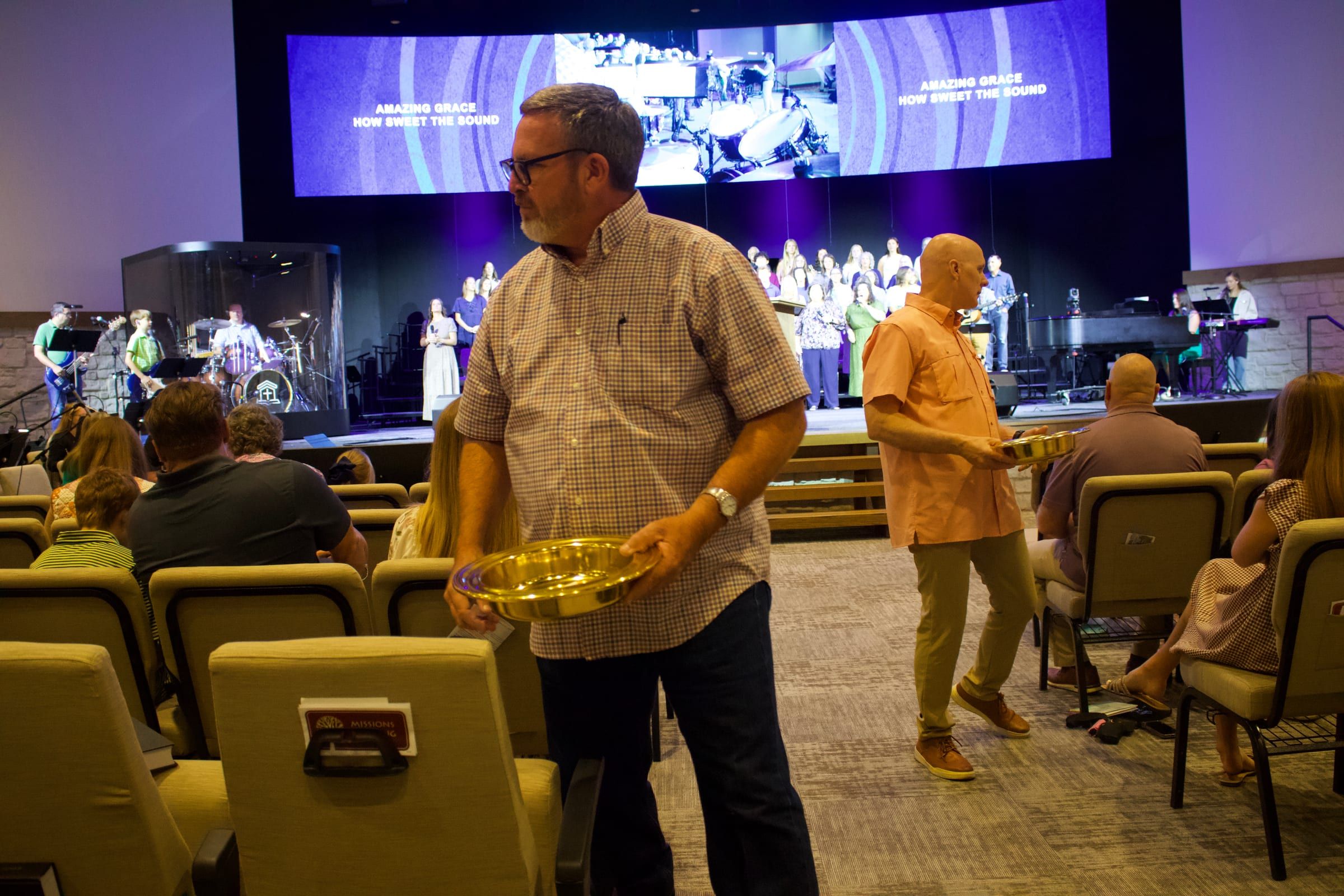 Ushers carrying the offering plates down the aisle during worship.