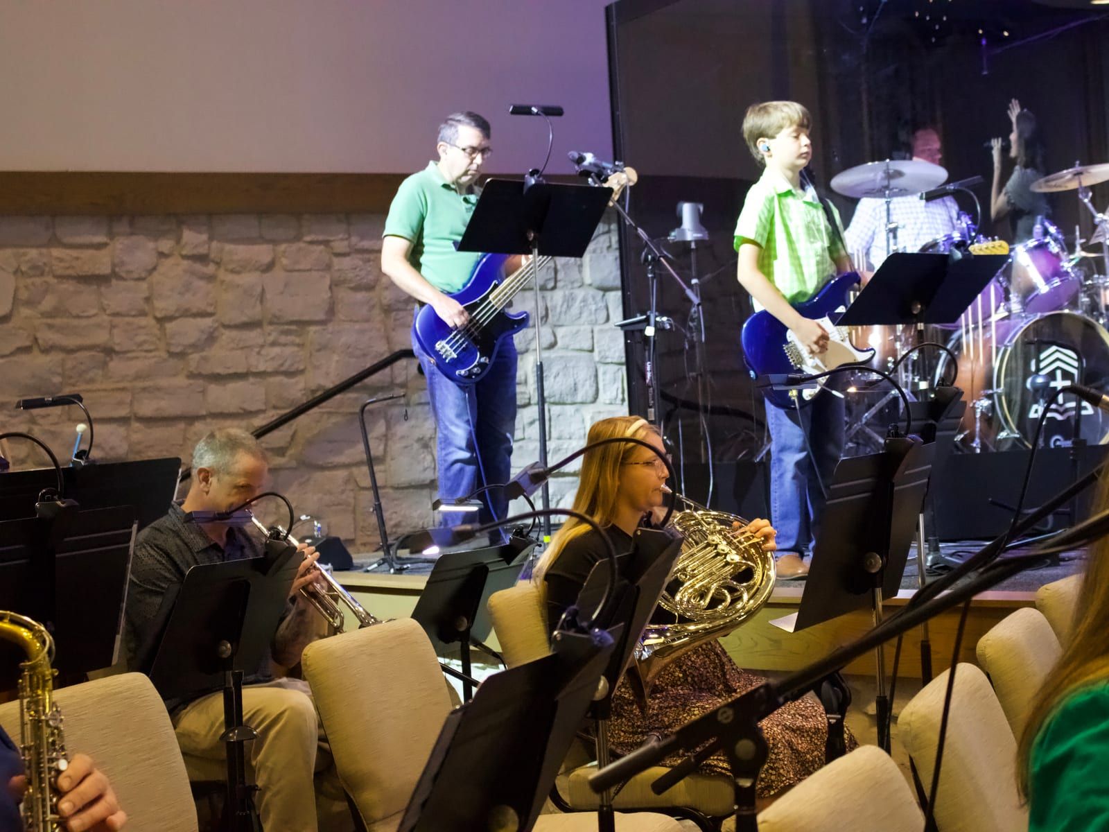 Instrumentalists playing on the platform — bass, guitar, drums, and horns.